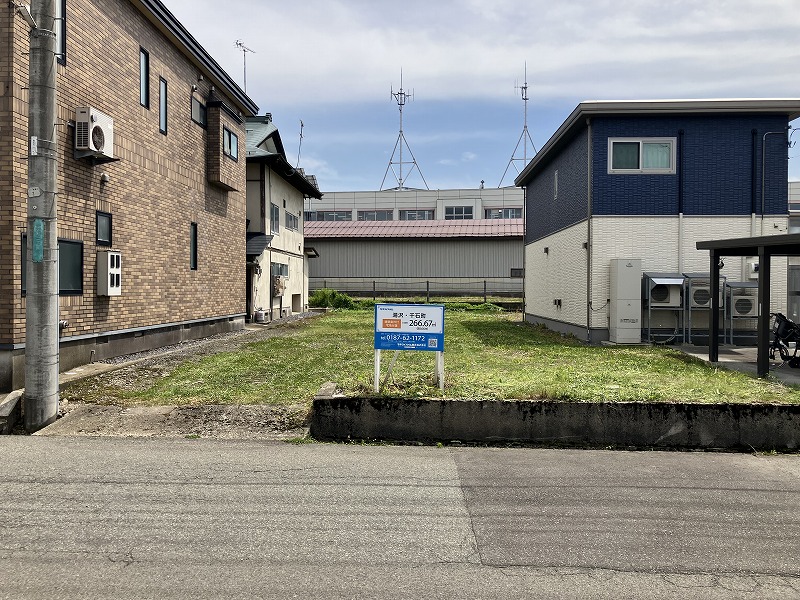 分譲地に建てられた看板には敷地面積266.67㎡と記載されています。住宅が背景に写っています。