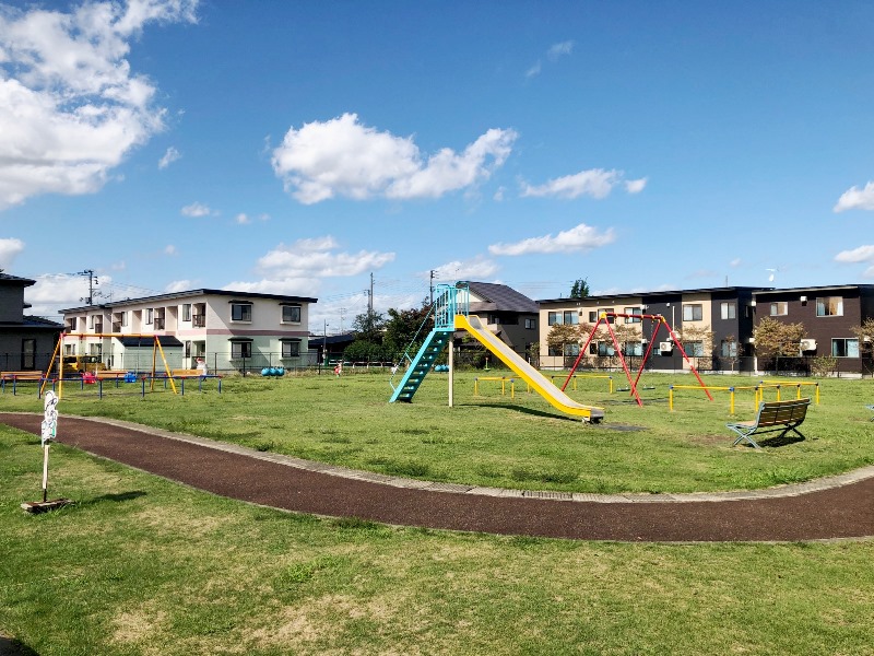 滑り台やブランコがある芝生の公園。住宅地に囲まれています。