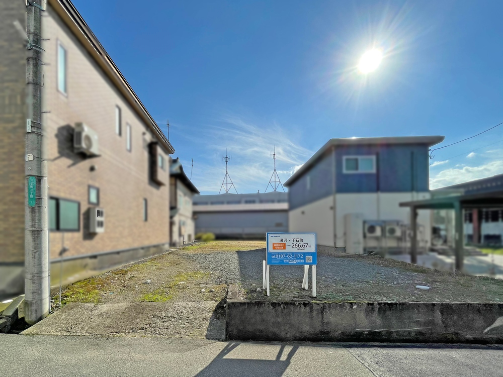 分譲地に建てられた看板には敷地面積266.67㎡と記載されています。住宅が背景に写っています。