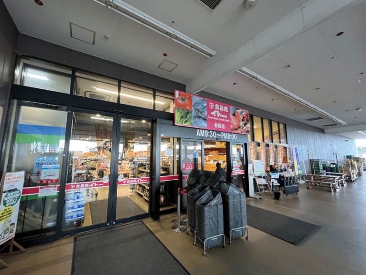 食品館イトー名取店の外観。ガラスドアの前にショッピングカートが置かれています。営業時間はAM9:30～PM8:00と書かれています。