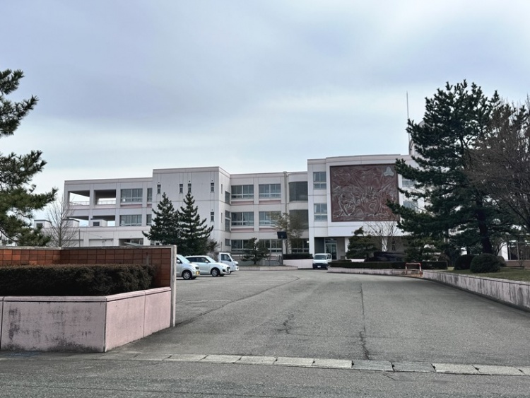 三階建ての白い押切小学校校舎の外観。正面に大きなレリーフがあります。