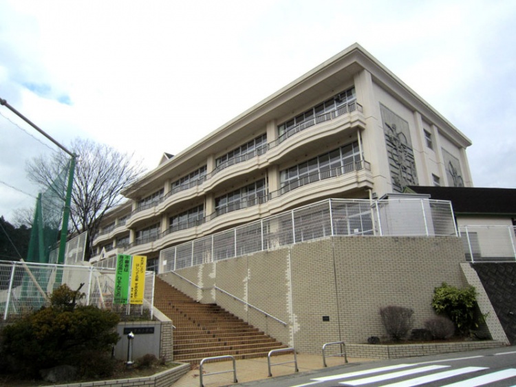 白い外壁の4階建て秋田市立寺内小学校の校舎の外観。正面には階段があり、フェンスに囲まれています。