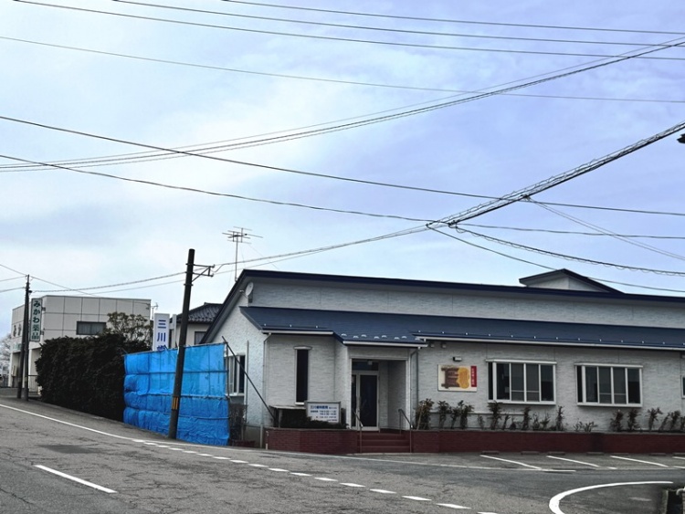 住宅街の角にあるネイビーの屋根の三川歯科の外観。手前には道路が見えます。