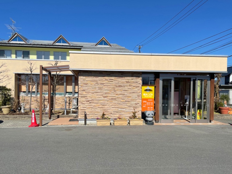 レンガ調とガラス扉が特徴的な橋本こどもクリニックの外観。入口にはオレンジ色の看板があります。