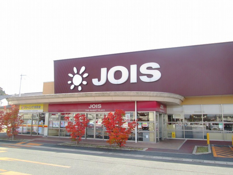 白とえんじ色が特徴的なジョイス三関店の看板があるスーパーマーケット。クリーニング店も併設されています。
