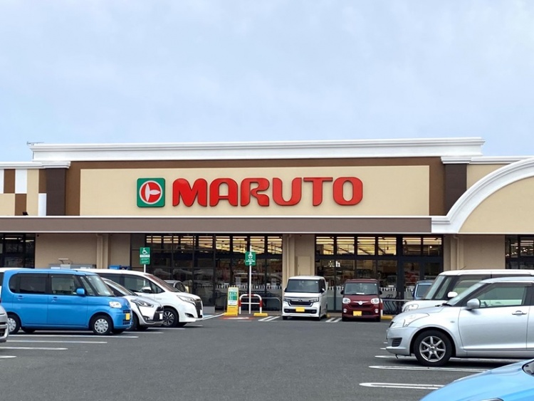 赤い文字が特徴的なマルト岡小名店の外観。駐車場にはたくさんの車が停められています。