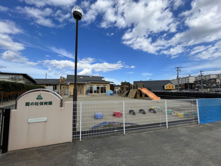 愛の杜保育園の外観。広い運動場があり遊具が設置されています。