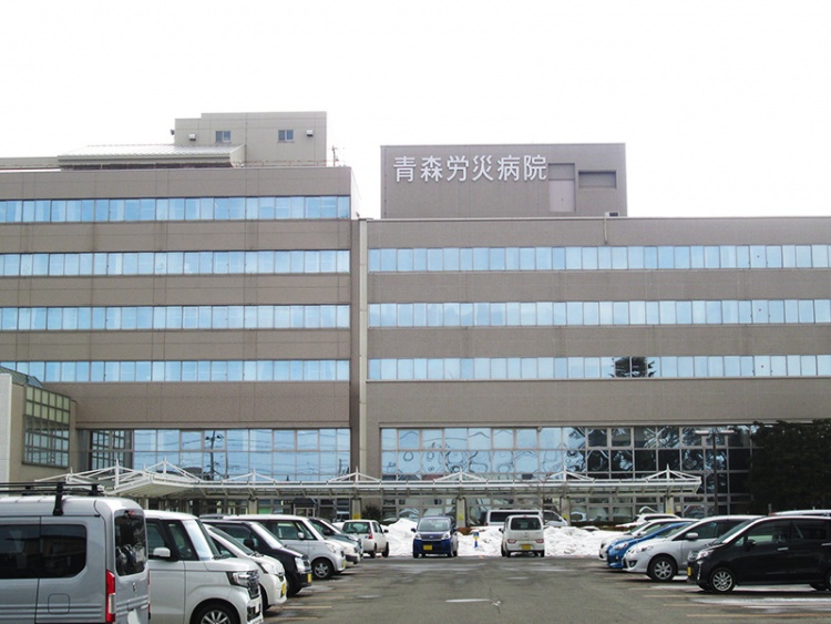 青森労災病院の建物外観と駐車場。正面には青森労災病院の看板があります。
