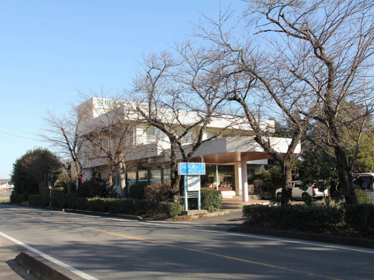 道路沿いに立つ石川小児科内科クリニックの建物の外観。周囲には木々が立ち並んでいます。