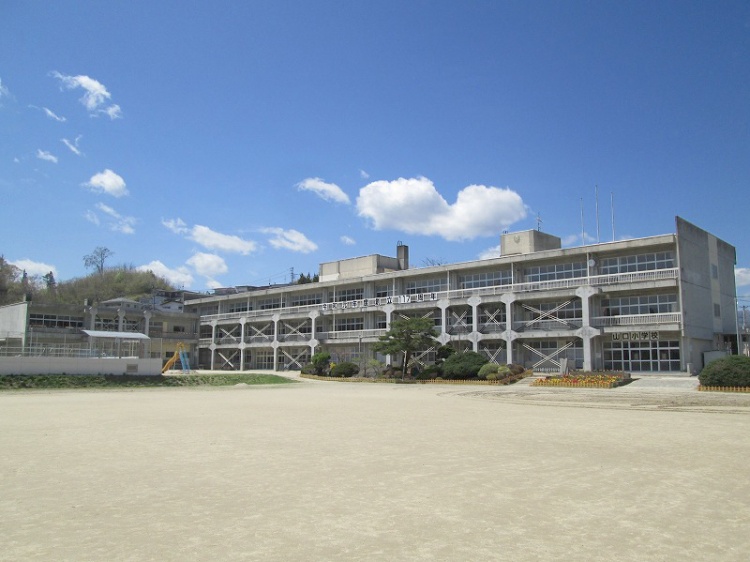 広々とした校庭に面した山口小学校の校舎。左奥には丘が見えます。