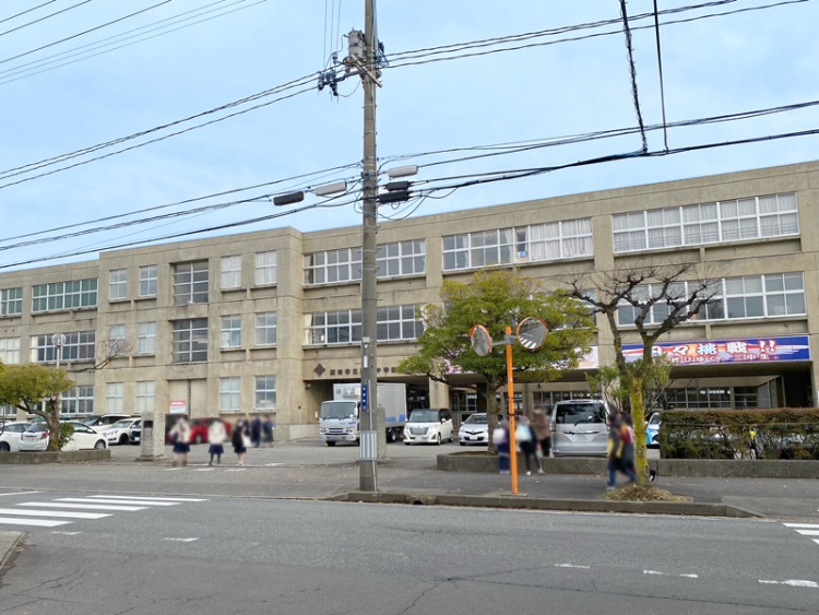 3階建ての酒田市立第三中学校校舎の外観。手前には電柱、植栽が植えられています。