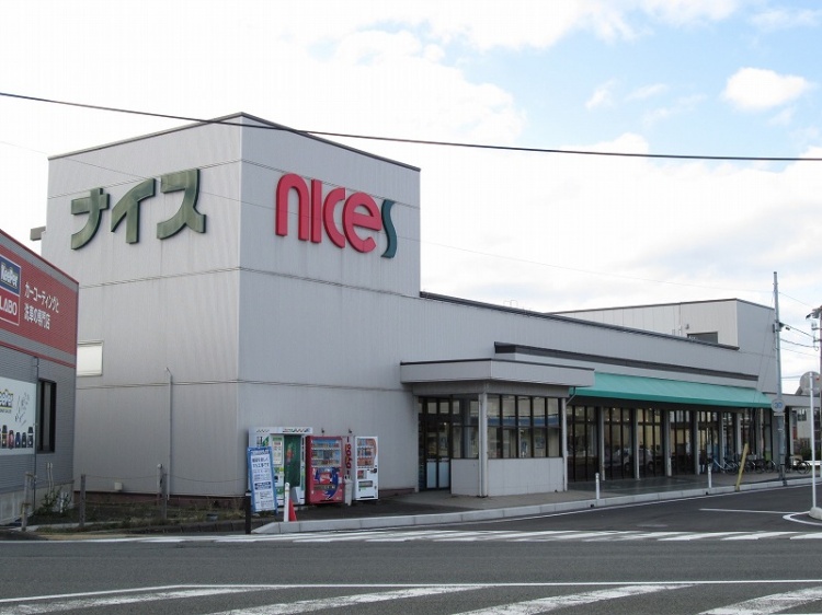 白い外壁にナイスとロゴがあるスーパーの店舗の外観。駐車のスペースもあります。