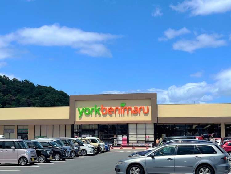 黄色い外壁が特徴的なヨークベニマル入江町店の外観。駐車場にはたくさんの車が停められています。