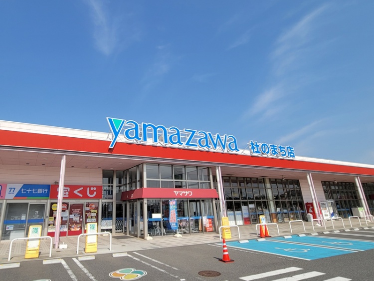 ヤマザワ杜のまち店の外観。青い看板とガラスの入口、駐車場も見えます。
