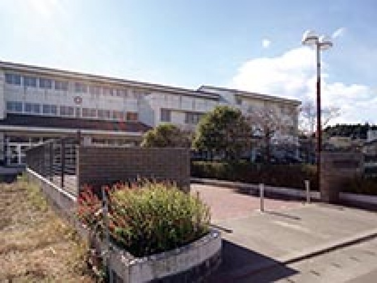 相馬市桜丘小学校の校舎の外観。前に植え込みと街灯があり、奥に木が植えられています。