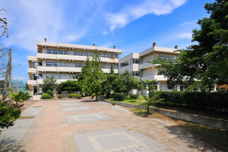 3階建ての郡山中学校校舎。校舎へ続く道と木々が見えます。
