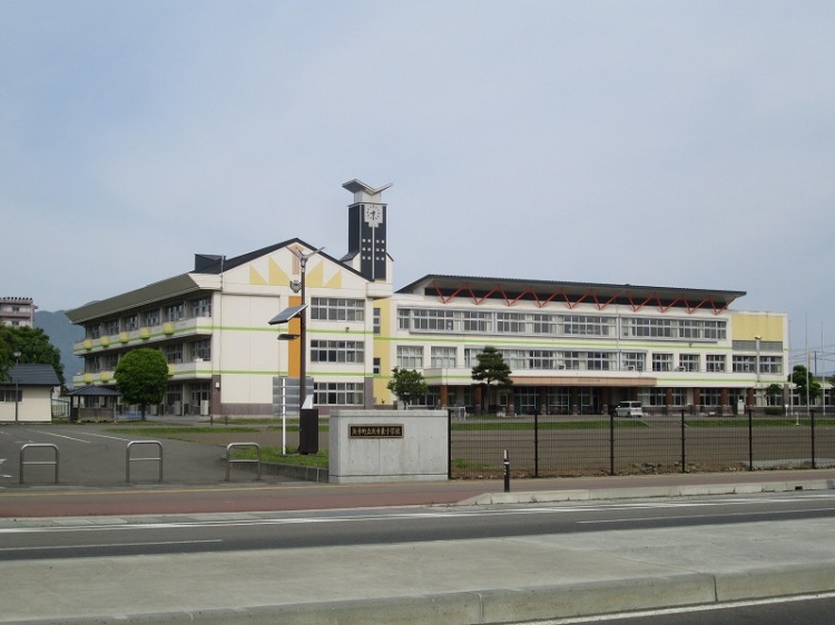 3階建ての矢巾東小学校校舎校舎の外観。手前には門があり、広い校庭が見えます。