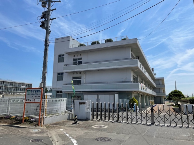 白い3階建ての仙台市立七北田小学校校舎の外観。手前には門があり、電柱も見えます。