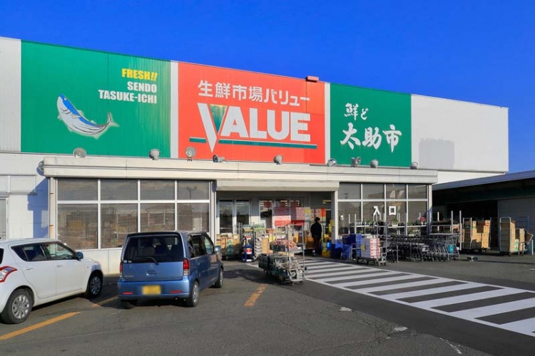 オレンジと緑の看板が特徴的な鮮ど太助市バリューの外観。駐車場には数台の車が停められています。