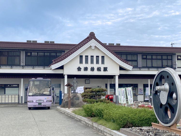 会津若松駅の駅舎。前景にバスと鉄道車輪のモニュメントが見えます。