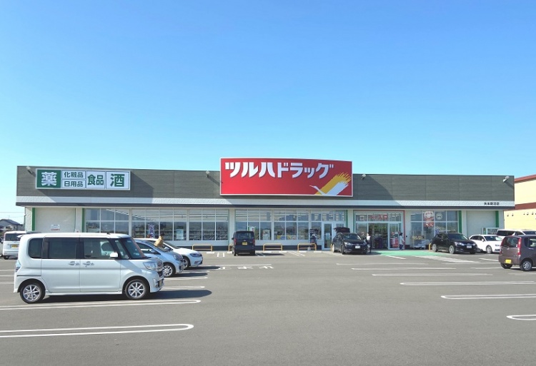 ツルハドラッグ矢本新沼店の外観。広い駐車場には数台の車が停められています。