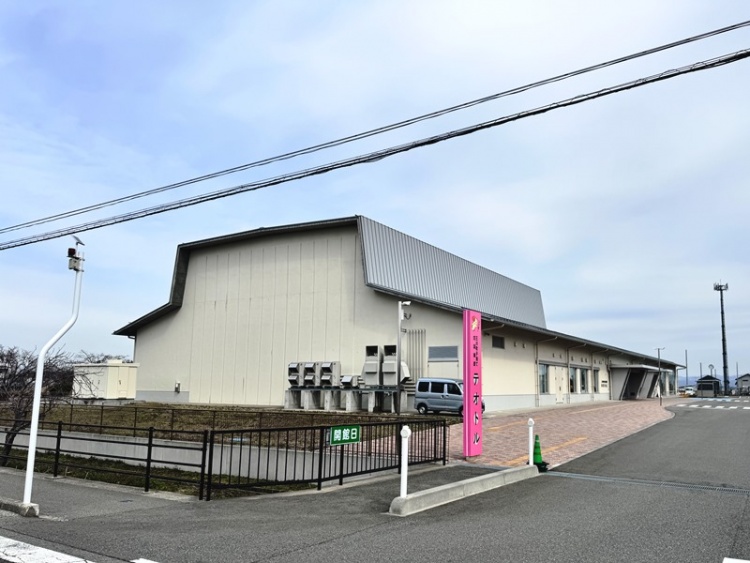 三川町子育て交流施設テオトルの外観。駐車場やピンクの看板が見えます。