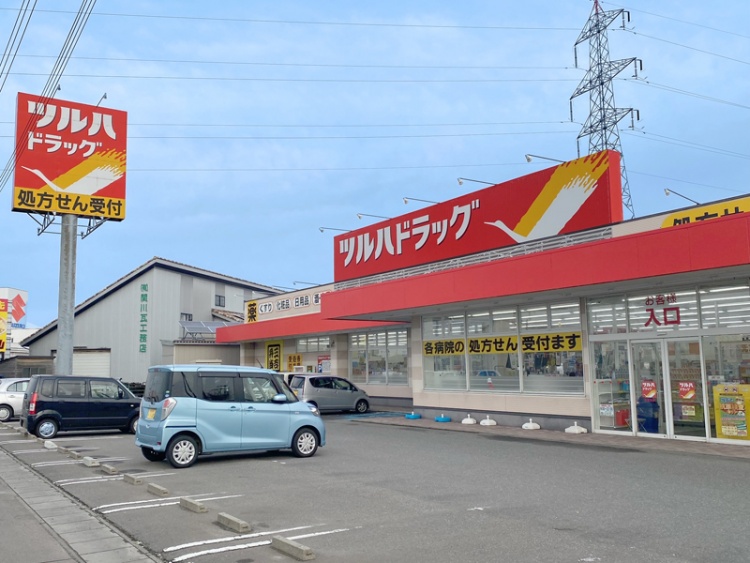 ツルハドラッグ酒田南店の外観。駐車場には数台の車が停められていて、処方せん受付の看板も見えます。
