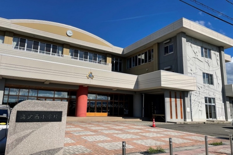 湯沢西小学校の校舎正面。右側に湯沢西小学校の石碑が設置されています。