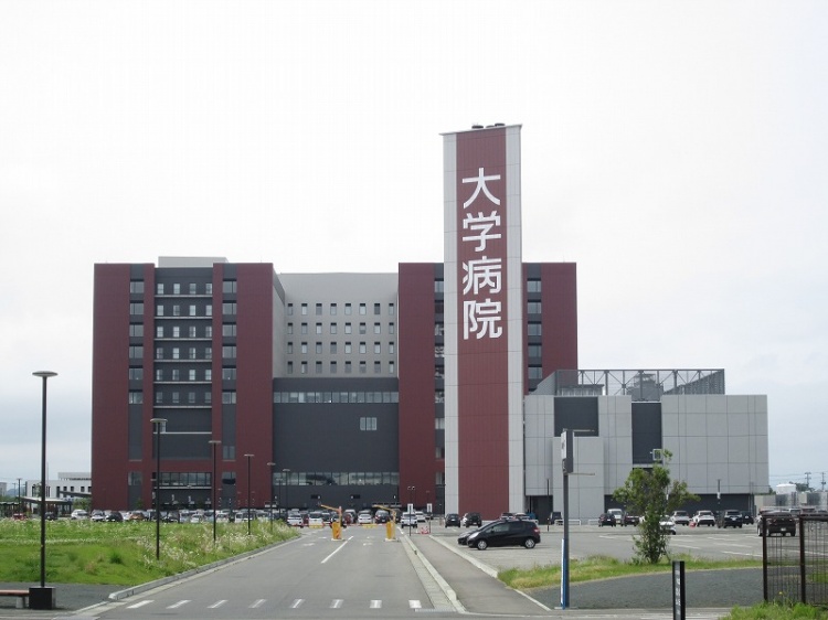 大きな建物の岩手医大附属病院の外観。広い駐車場には複数の車が停められています。