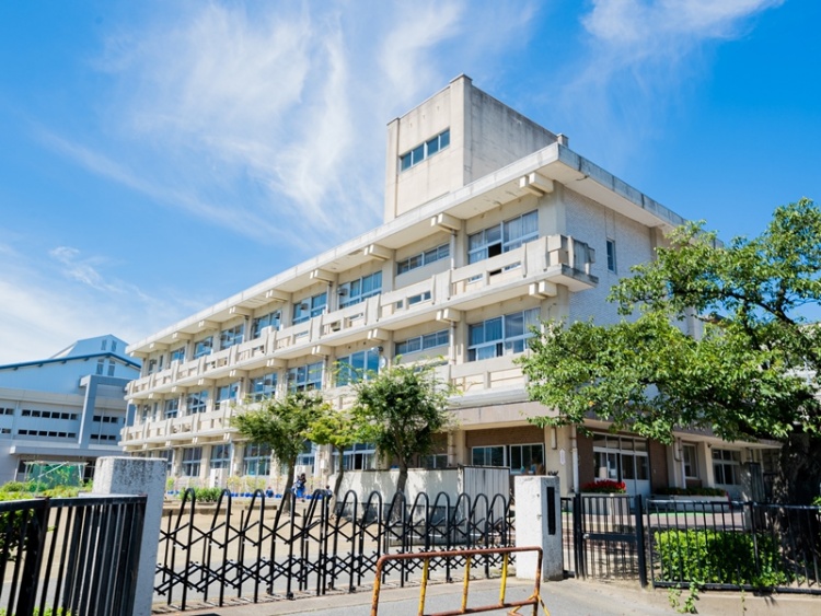 鉄製の門とフェンスに囲まれた吉井田小学校の校舎の外観。校庭には木が植えられています。