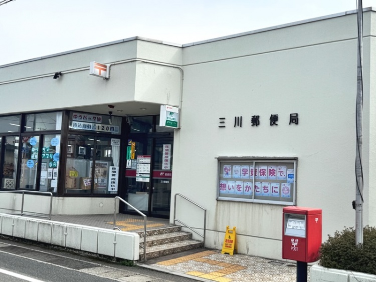 三川郵便局の外観。入口の横には赤い郵便ポストが設置されています。