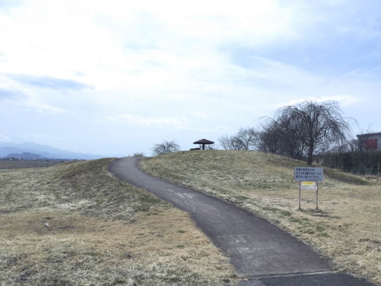 小さな丘に続く山形空港ひこうき公園の外観。丘の頂上にある木製の東屋が見えます。
