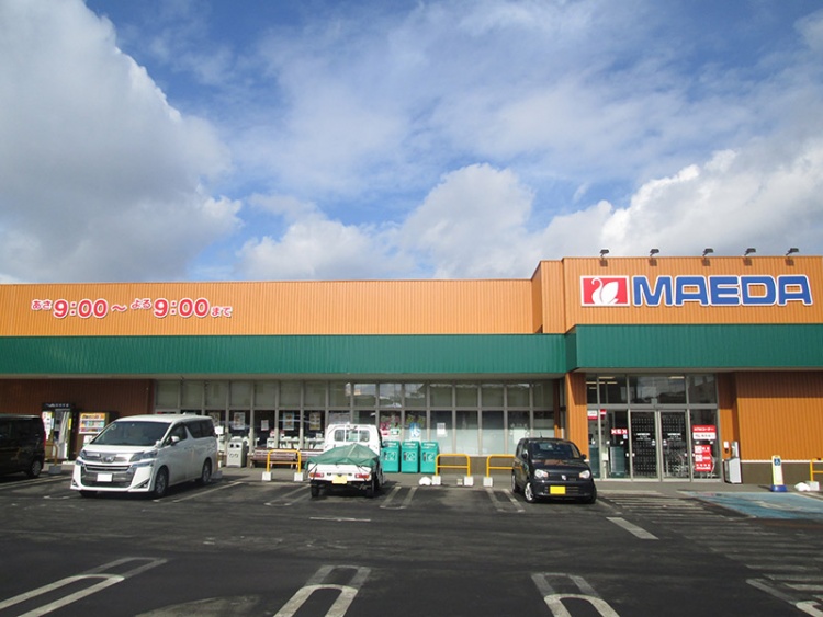 駐車場に車が数台停まっているマエダストア大久保店の外観です。営業時間は9:00～21:00と表示されています。