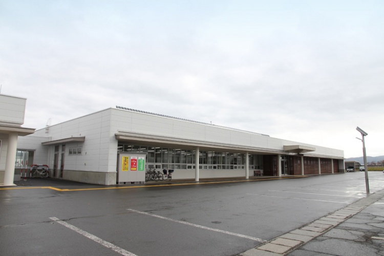 白い建物の横手市役所平鹿地域局の外観。駐車場が隣接していて、建物前には自転車が数台停められています。