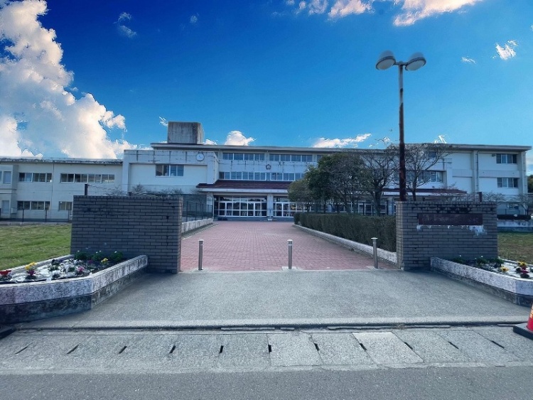 桜丘小学校の校舎の外観。手前に門が見え校舎に続く赤の道が見えます。