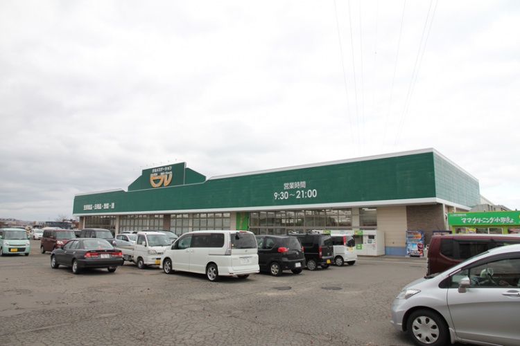 緑色の看板が特徴的なビフレ横手店の外観。駐車場に車が数台停まっています。建物上部には営業時間は9:30～21:00と書かれています。