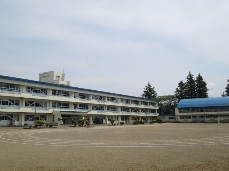 徳田小学校の校舎と校庭。校庭には運動用のトラックが描かれている。校舎は3階建て。