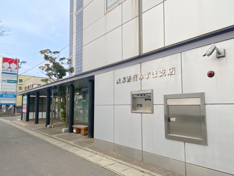 山形銀行みずほ支店の外観。ATMや防犯カメラが設置されていて、隣に別の看板も見えます。