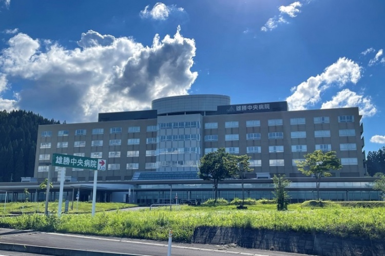 大きな建物の雄勝中央病院の外観。手前に雄勝中央病院の案内標識があります。
