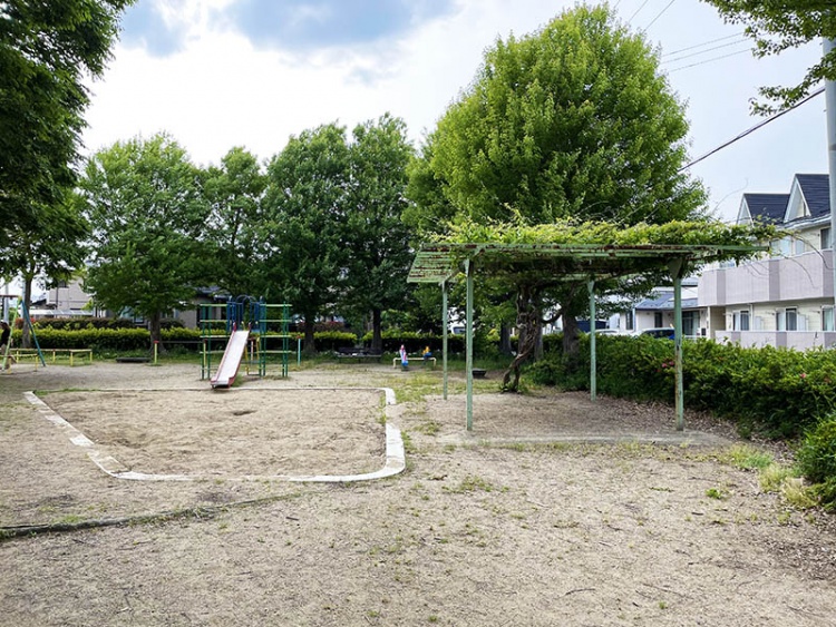 亀田公園。遊具、木々がみえ、周辺には住宅が見えます。