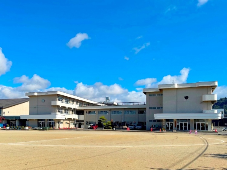 3階建ての一箕小学校校舎の外観。広い校庭が見えます。