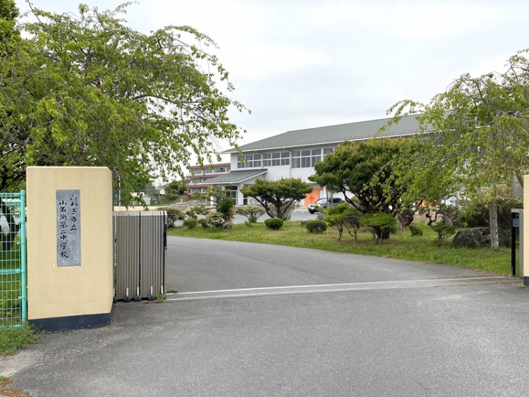黄色の門が特徴的ないわき市立小名浜第二中学校校舎の外観。門の奥には木々が生えています。