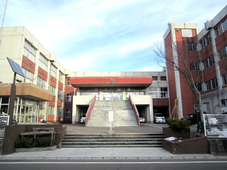 赤と白の外壁の泉中学校の校舎の外観。正面にある階段が写っています。