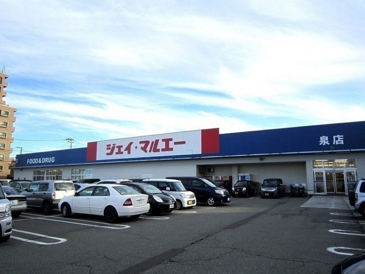 青い看板のジェイ・マルエー泉店の外観。駐車場に複数の車が停まっています。