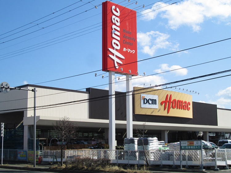 DCMホーマック類家店の外観です。高い縦看板と入り口付近に園芸用品が積まれています。