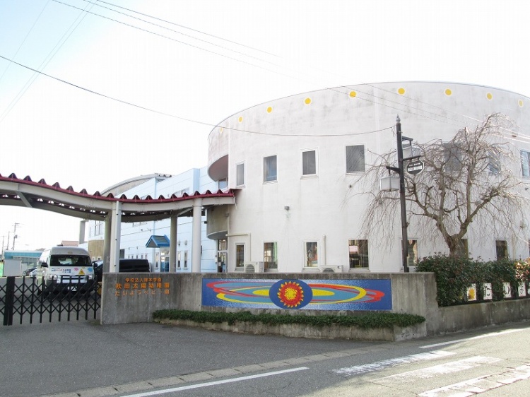 白い円形の建物が特徴的な太陽幼稚園の外観。壁に太陽の絵が描かれています。