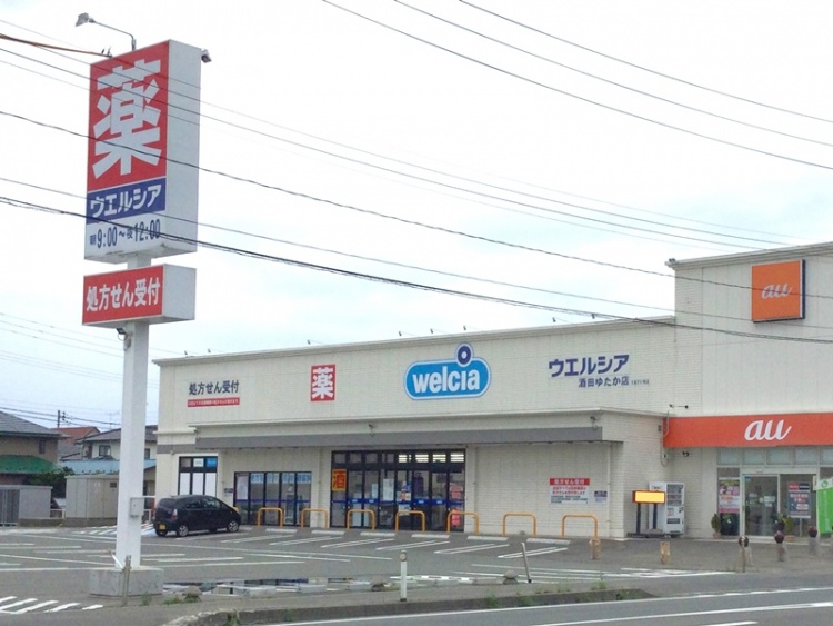 ウエルシア酒田ゆたか店の外観。9:00～24:00営業で、処方箋受付が有ります。隣にau店舗も見えます。
