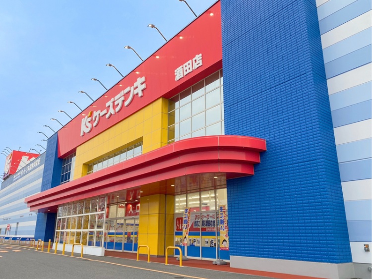 赤と青と黄色が特徴的なケーズデンキ酒田店の外観。旗がたっています。