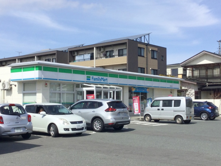 ファミリーマートの東根神町店の外観。駐車場には数台の車が停められています。背景には住宅が見えます。