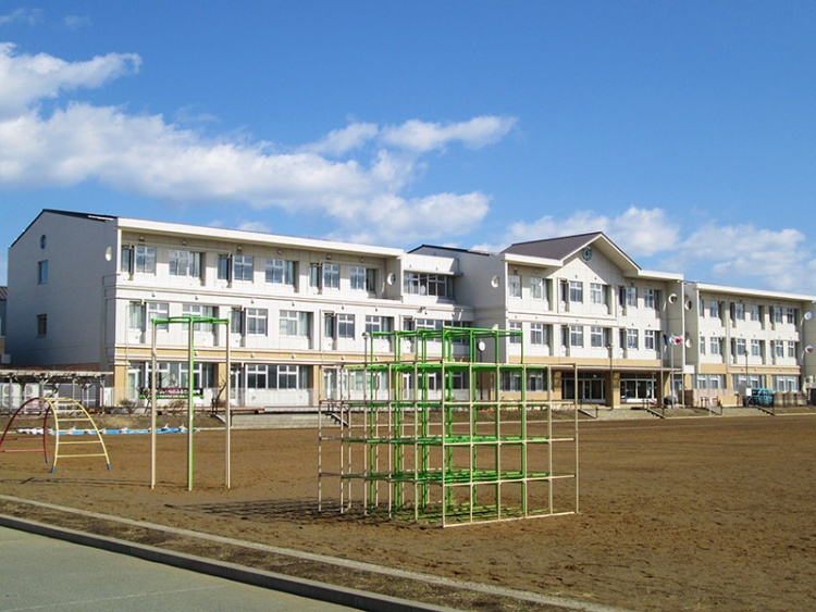 柏崎小学校の校舎と校庭の遊具が写っている写真です。